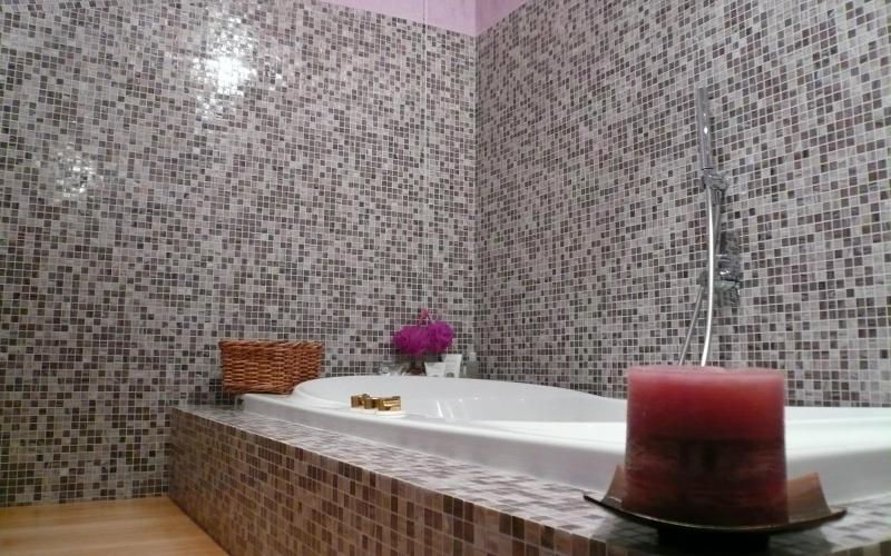 Rivestimento in mosaico grigio in bagno con pavimento in legno