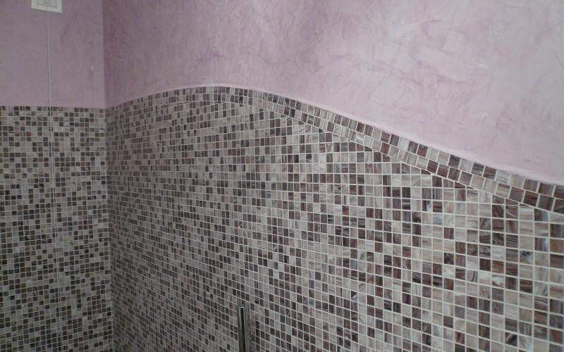 Rivestimento in mosaico grigio in bagno con pavimento in legno
