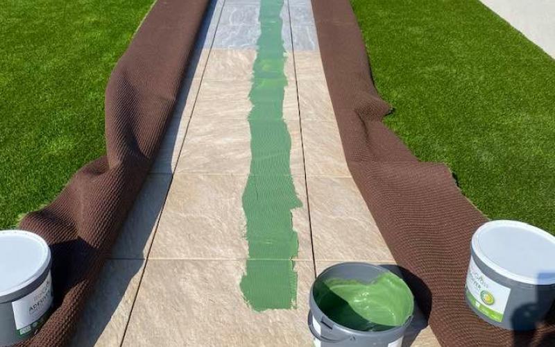 Incollaggio dell'erba sintetica sulle piastrelle nel tetto del capannone