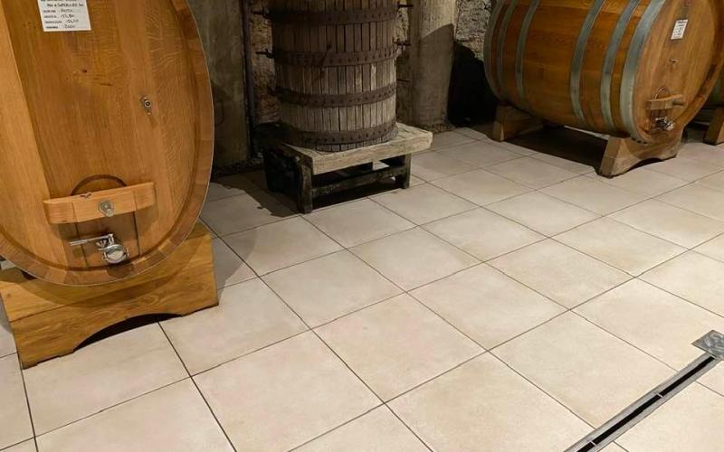 Pavimento in grès chiaro per cantina vinicola con botti in legno