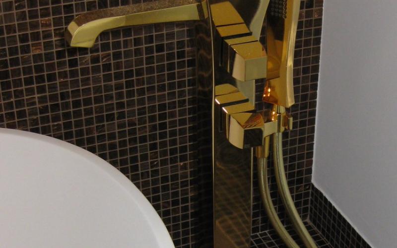 Il rubinetto oro nella zona vasca e la parete rivestita in mosaico