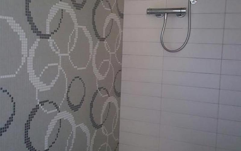 bathroom with grey mosaic shower wall in circles