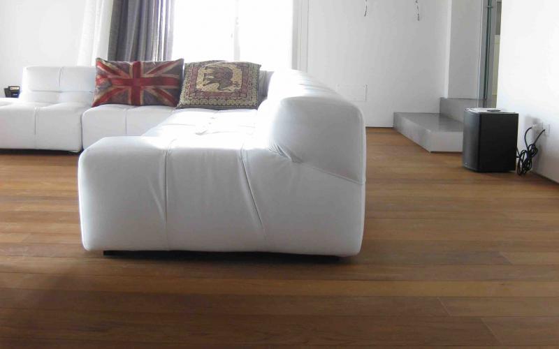 Pavimento in legno nel salone in contrasto con divano bianco