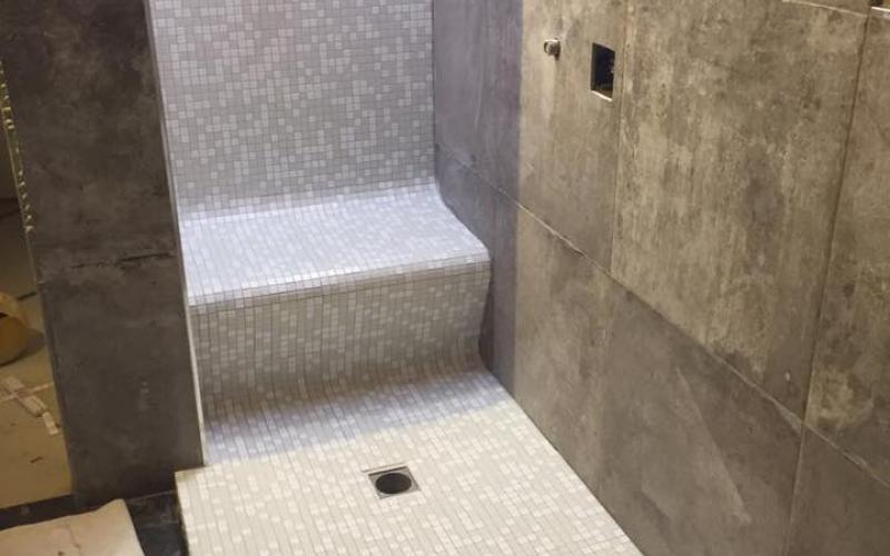 A shower tray and shower seat made of mosaic in a bathroom in Vicenza by pellizzari